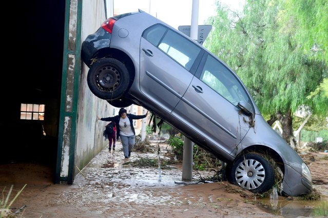 A resident walks next to a car lifted up in a street covered in mud in a flooded area in Picanya, near Valencia, eastern Spain, on October 30, 2024. Floods triggered by torrential rains in Spain's eastern Valencia region has left 51 people dead, rescue services said on October 30. (Photo by Jose Jordan/AFP Photo)