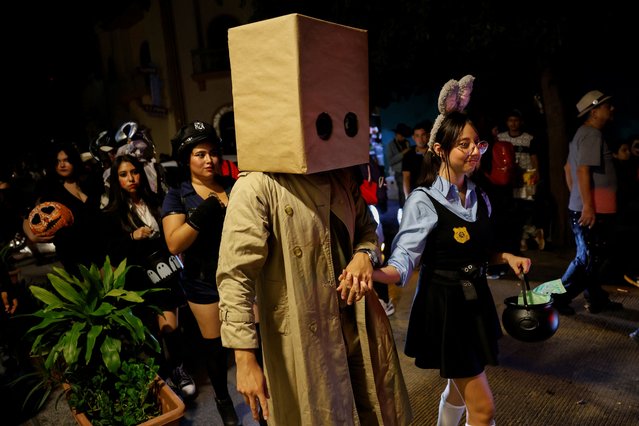 People in costumes walk in a bar area during Halloween evening, in Monterrey Mexico on November 1, 2024. (Photo by Daniel Becerril/Reuters)
