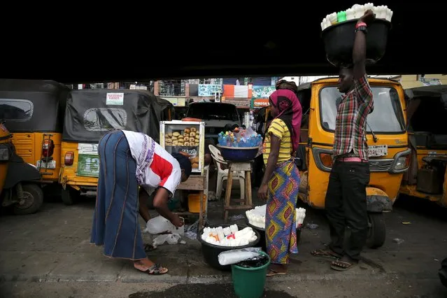 Vendors sell their wares under a bridge where commercial tricycles are parked in Obalende district in Nigeria's commercial capital Lagos November 23, 2015. (Photo by Akintunde Akinleye/Reuters)