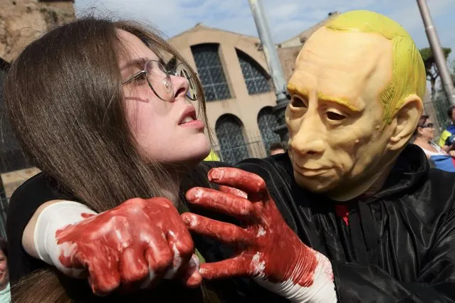 A man in Putin mask and bloody hands attempts to strangles a girl during Flashmob demonstration of the Ukranian Community of Rome, Italy on May 1, 2022. (Photo by Evandro Inetti/ZUMA Press Wire/Rex Features/Shutterstock)