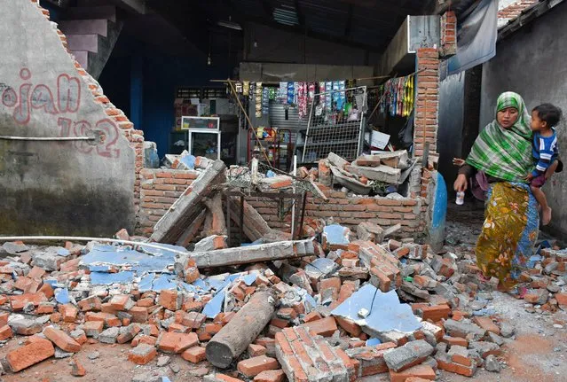 A woman walks past debris from a collapsed wall following a strong earthquake in Lendang Bajur Hamlet, Lombok island, indonesia  August 6, 2018 in this photo taken by Antara Foto. (Photo by Ahmad Subaidi/Antara Foto via Reuters)