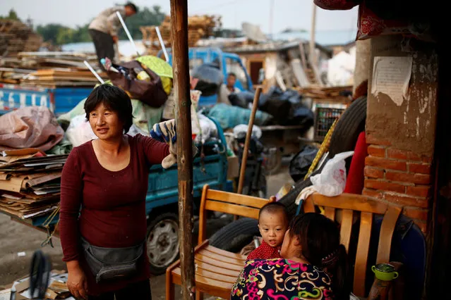 Huan (R) and her son Peijun sit outside their hut as they talk with a neighbour at a recycling yard at the edge of Beijing, China, September 21, 2016. (Photo by Thomas Peter/Reuters)