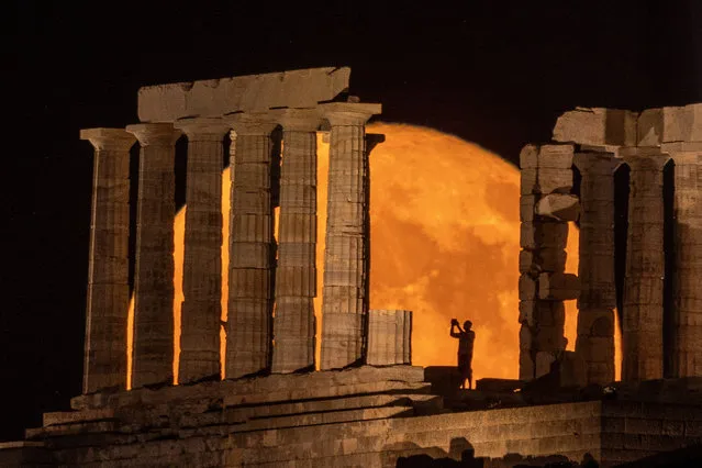 A person takes a photo as a full moon known as the “Buck Moon” rises behind the Temple of Poseidon, in Cape Sounion, near Athens, Greece on July 3, 2023. (Photo by Alkis Konstantinidis/Reuters)