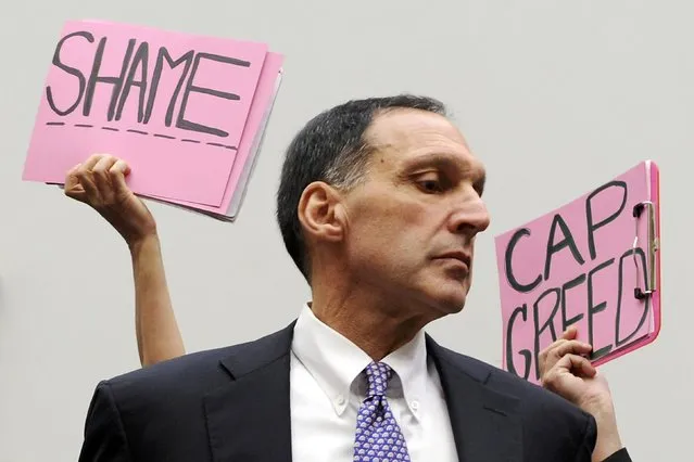 Protestors hold signs behind Richard Fuld, Chairman and Chief Executive of Lehman Brothers Holdings, as he takes his seat to testify at a House Oversight and Government Reform Committee hearing on the causes and effects of the Lehman Brothers bankruptcy, on Capitol Hill in Washington in this October 6, 2008 file photo. (Photo by Jonathan Erns/Reuters)