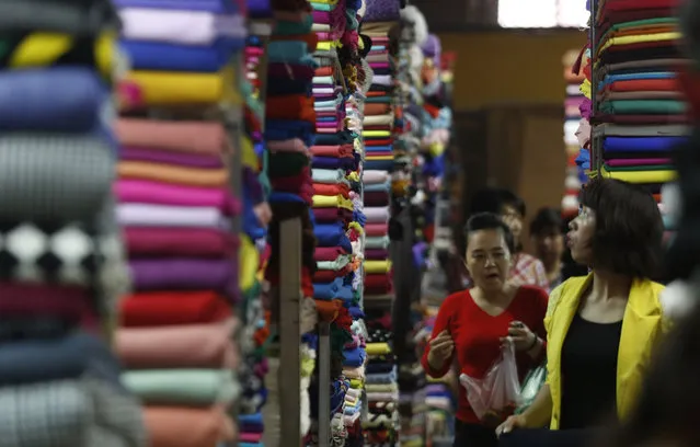 Customers walk along fabric rolls which are displayed for sale at a market in Hanoi, Vietnam December 24, 2015. (Photo by Reuters/Kham)