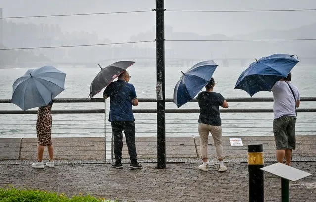 People struggle with their umbrellas in high winds brought by Super Typhoon Saola in Heng Fa Chuen in Hong Kong on September 1, 2023. Super Typhoon Saola threatened southern China on September 1 with some of the strongest winds the region has endured, forcing the megacities of Hong Kong and Shenzhen to effectively shut down. (Photo by Mladen Antonov/AFP Photo)