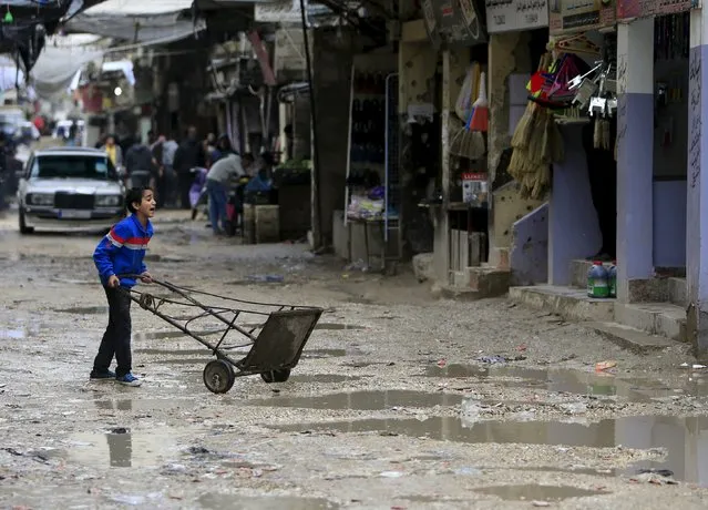 A boy pushes a cart amid water puddles in Ain al-Hilweh Palestinian refugee camp, near the port-city of Sidon, southern Lebanon January 19, 2016. (Photo by Ali Hashisho/Reuters)