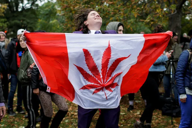 A man dances with a marijuana flag at Trinity Bellwoods Park, in Toronto, Ontario on October 17, 2018. Canada became the largest country with a legal national marijuana marketplace as sales began early Wednesday. (Photo by Carlos Osorio/Reuters)