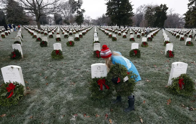 Madeline Espinosa, 11, of Bethesda, Md., places a wreath at a grave as part of Wreaths Across America at Arlington National Cemetery, Saturday, December 17, 2016 in Arlington, Va. Organizers estimate more than 245,000 wreaths were placed at graves throughout the cemetery. (Photo by Alex Brandon/AP Photo)
