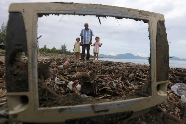 A man and two chidlren walk among garbage that washed ashore on Kampung Jawa beach in Banda Aceh, Indonesia. 02 June 2021. Tons of plastic garbage, mostly water bottles and food packaging coming from a urban river, washed ashore after reaching the open sea. (Photo by Hotli Simanjuntak/EPA/EFE)