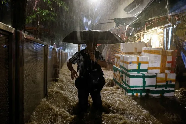 A man walks past a flooded area during heavy rain in Hong Kong, China on September 8, 2023. (Photo by Tyrone Siu/Reuters)