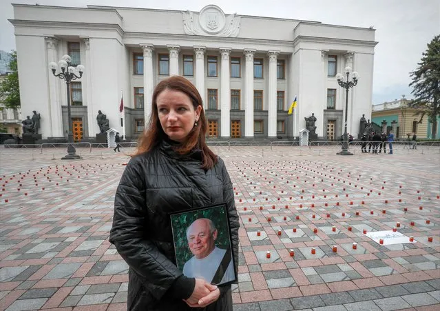 A woman holds a portrait of her father near the candles commemorating 47000 victims of the coronavirus disease (COVID-19) during a protest demanding the resignation of Ukrainian Health Minister Maksym Stepanov in front of the parliament building in Kyiv, Ukraine on May 17, 2021. (Photo by Gleb Garanich/Reuters)