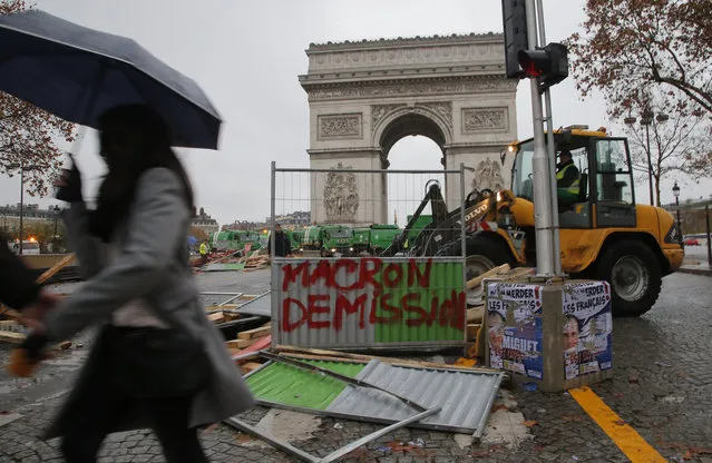 A bulldozer cleans the street from a barricade in the aftermath of a protest against the rising of the fuel taxes at the Champs Elysees avenue in Paris, France, Sunday, November 25, 2018. French President Emmanuel Macron has condemned violence by protesters at demonstrations against rising fuel taxes and his government. Tag on the barricade reads, “Macron resignation”. (Photo by Michel Euler/AP Photo)