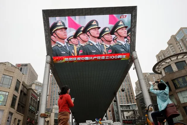 People take pictures of a screen showing the celebration marking the 100th founding anniversary of the Communist Party of China, in Beijing, China on July 1, 2021. (Photo by Thomas Peter/Reuters)