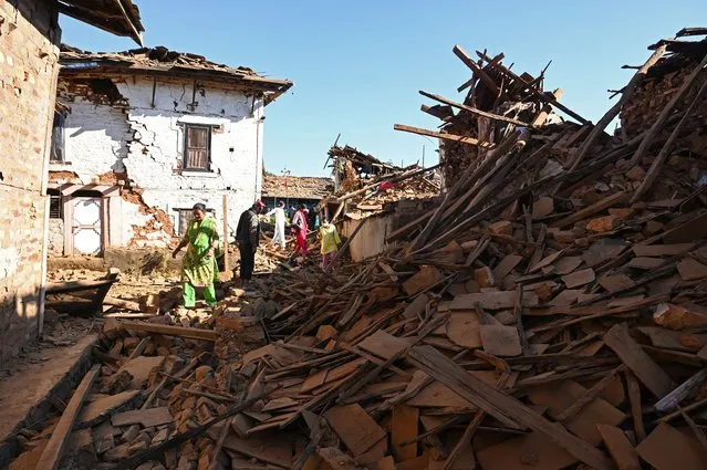 People walk through ruins of houses in the aftermath of an earthquake at Jajarkot district on November 4, 2023. At least 132 people were killed in an overnight earthquake of 5.6-magnitude that struck a remote pocket of Nepal, officials said on November 4, as security forces rushed to assist with rescue efforts. (Photo by Prakash Mathema/AFP Photo)