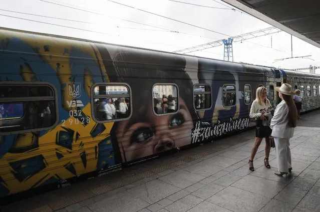 Ukrainians stand near the train named The Train to Victory at the railway station in Kyiv, Ukraine, 23 August 2022. The Train to Victory project consists of seven train cars painted by Ukrainian artists. Each car is dedicated to the temporarily occupied territories of Ukraine and the feats of Ukrainians resisting Russian invasion. The Train to Victory left Kyiv for its first trip and will arrive in the Western Ukrainian city of Uzhgorod on Independence Day on 24 August. (Photo by Sergey Dolzhenko/EPA/EFE)