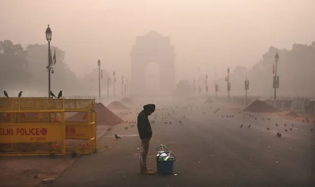 In this Wednesday, December 26, 2018, photo, a boy selling tea awaits customers early morning amidst smog in New Delhi, India. Authorities have ordered fire services to sprinkle water from high rise building to settle dust particles and stop burning of garbage and building activity in the Indian capital as the air quality hovered between severe and very poor this week posing a serious health hazard for millions of people. (Photo by Manish Swarup/AP Photo)