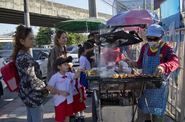 In this Thursday, Novenber 1, 2018, photo, school children gather around street vendors outside their school in Bangkok, Thailand. A report by the United Nations Food and Agricultural Organization released Friday, Nov. 2,  says some 486 million people are malnourished in Asia and the Pacific, and progress in alleviating hunger has stalled. (Gemunu Amarasinghe/AP Photo)