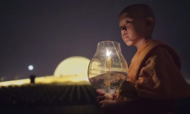 A Buddhist novice holds a candle during a ceremony at the Dhammakaya Temple in Bangkok on February 22, 2016 on the occasion of Makha Bucha day. The Makha Bucha festival is observed in Thailand on the full moon of the third lunar month and commemorates the day when 1,250 monks gathered to be ordained by the Buddha. (Photo by Nicolas Asfouri/AFP Photo)