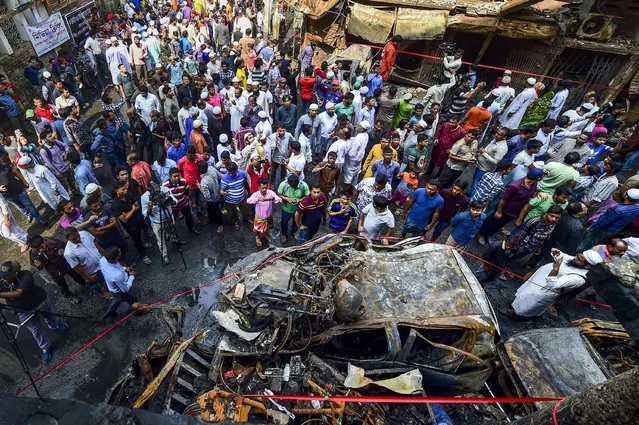 Bangladeshi people gather around the wreckage of cars that burnt in a fire in Dhaka, Bangladesh's capital city, on February 22, 2019. Funerals started on February 22 for victims of a devastating fire in a historic district of Dhaka that killed almost 70 people burned alive by exploding chemical canisters and trapped by flames. (Photo by Munir Uz Zaman/AFP Photo)
