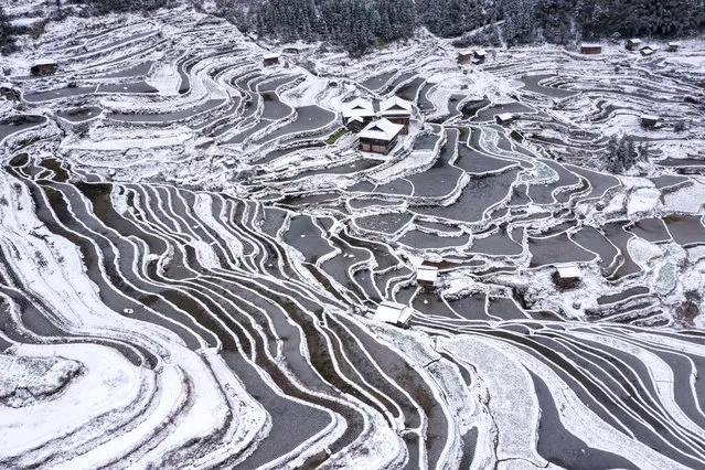 The aerial view shows snow-covered terraced fields and houses in Congjiang county, in China's southwestern Guizhou province on January 22, 2024. (Photo by AFP Photo/China Stringer Network)