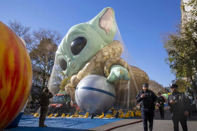 Police walk by an inflated helium balloon of Grogu, also known as Baby Yoda, from the Star Wars show The Mandalorian, Wednesday, November 24, 2021, in New York, as the balloon is readied for the Macy's Thanksgiving Day Parade on Thursday. (Photo by Ted Shaffrey/AP Photo)