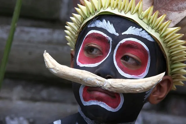 A boy painted his face as he participate in Hindu ritual of Ngerebeg at Tegallalang village in Bali, Indonesia on Wednesday, April 3, 2024. In this ritual, participants paint their bodies with colorful paint and parade around their village to ward off evil spirits and bring happiness to the village. (Photo by Firdia Lisnawati/AP Photo)