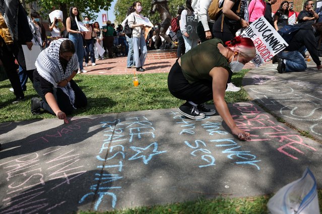 Pro-Palestinian protesters write messages with chalk as others begin to build an encampment at California State University of Los Angeles in Los Angeles, California, on May 1, 2024. (Photo by Aude Guerrucci/Reuters)