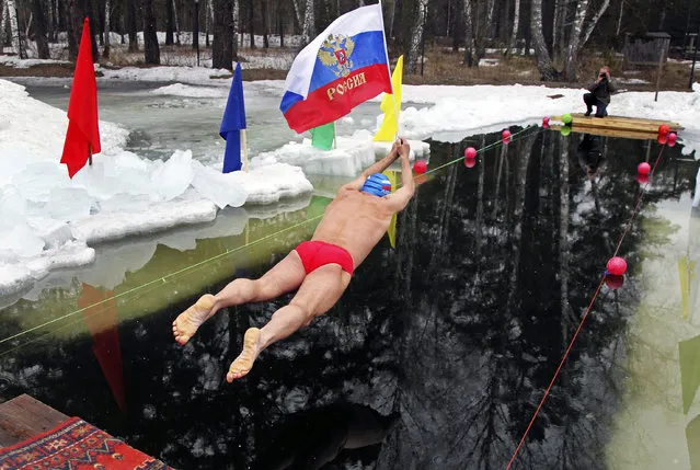 A member of a local swimming club holds a Russian national flag as he dives in at the start of a 24-hour swimming marathon near the western Siberian city of Barnaul March 29, 2014. Thirty members of the club will swim in turn during the event, held to mark Crimea becoming part of Russia, local media reported. (Photo by Andrei Kasprishin/Reuters)