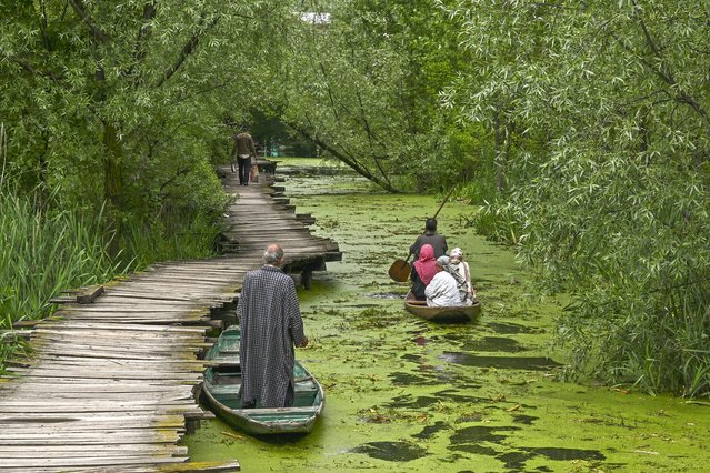 A boatman (R) steers a boat with residents along a canal in the interior of Dal Lake after water levels rose due to heavy rains, in Srinagar on April 30, 2024. (Photo by Tauseef Mustafa/AFP Photo)