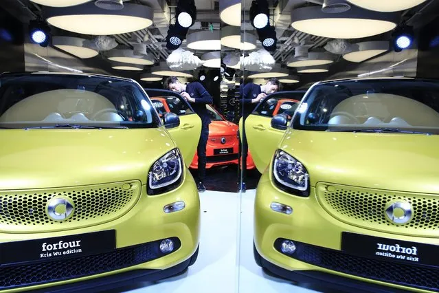 A staff member cleans a Daimler AG Smart Forfour and is reflected in a mirror during an event showcasing the Smart Forfour and world premiere of the Brabus Fortwo at the Mercedes Me store ahead of the Auto China 2016 exhibition in Beijing, China, 24 April 2016. The 14th Beijing International Automotive exhibition or Auto China 2016 will run from 25 April to 04 May 2016. (Photo by How Hwee Young/EPA)