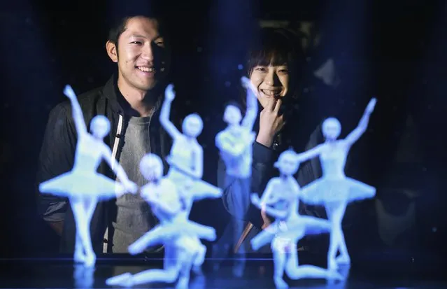 Tomoaki Ishizuka, left, and Yurika Yonekura, right, watch the hologram of Japanese skater Yuzuru Hanyu, center, with ballet dancers with their scanned faces attached at newly opened Hologram Dance Theater at Madame Tussauds in Tokyo, Thursday, April 28, 2016. Madam Tussauds in Tokyo is launching an event allowing visitors to virtually join a 3D world to dance with holograms of celebrities such as Brad Pitt, Leonardo DiCaprio, and Lady Gaga. (Photo by Eugene Hoshiko/AP Photo)