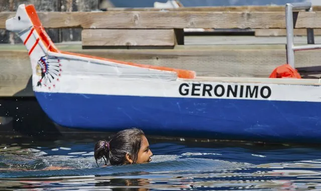 A female First Nations competitor swims past the Geronimo canoe prior to the first war aboriginal canoe race in over 100 years in the Inner Harbour of Victoria June 27, 2015.  Greater Victoria Harbour Authority, in partnership with Esquimalt Nation and Songhees Nation, staged the event off Ku-Sing-ay-la, the traditional village site of the Lekwungen people in the Inner Harbour, for the first time since 1908. (Photo by Kevin Light/Reuters)