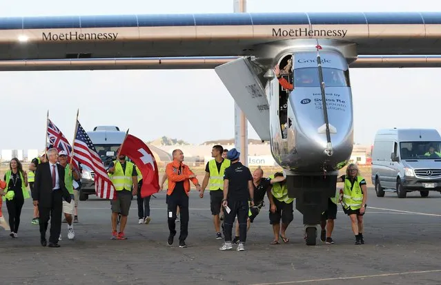Pilot Andre Borschberg waves to the crowd as he is escorted by pilot Bertrand Piccard (L) and the Swiss Ambassador to the U.S. Martin Dahinden (front L) after the Solar Impulse 2 airplane landed at Kalaeloa airport after flying non-stop from Nagoya, Japan in Kapolei, Hawaii, July 3, 2015. (Photo by Hugh Gentry/Reuters)