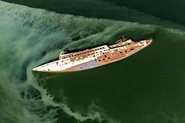 This aerial image shows the capsized hull of the Al Mansur (Victorious), a private yacht of former Iraqi dictator Saddam Hussein, in the Shatt al-Arab waterway, in Iraq's southern city of Basra, on February 28, 2023. The Al-Mansur now lays on its side, having capsized 20 years ago after it was struck during the 2003 US-led invasion of Iraq that ended Saddam's decades of iron-fisted rule. (Photo by Hussein Faleh/AFP Photo)