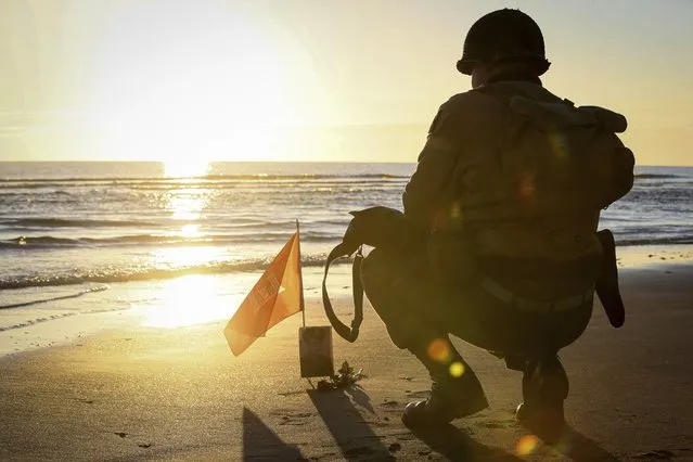 A World War II reenactor pays tribute to a soldier on Omaha Beach in Saint-Laurent-sur-Mer, Normandy, Sunday, June 6, 2021, the day of 77th anniversary of the assault that helped bring an end to World War II. While France is planning to open up to vaccinated visitors starting next week, that comes too late for the D-Day anniversary. So for the second year in a row, most public commemoration events have been cancelled. (Photo by David Vincent/AP Photo)