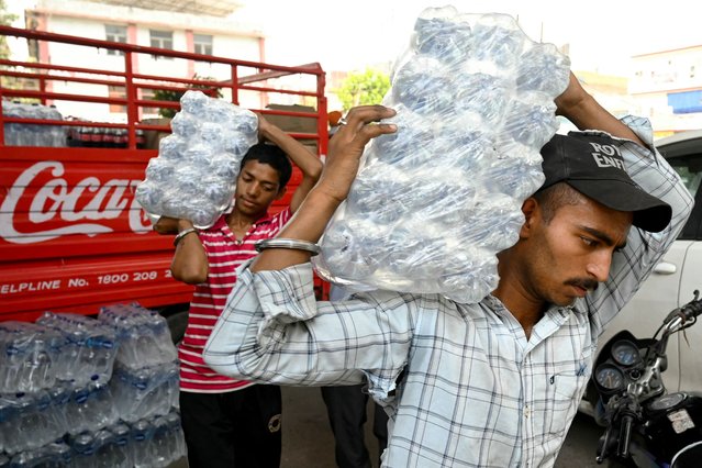 Workers unload water bottles from a mini truck on a hot summer day in Amritsar on June 15, 2024 amid heatwave. (Photo by Narinder Nanu/AFP Photo)