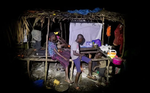 The hunters and their children rest at night after paddling for eight hours to get to their campsite in the forest near Mbandaka, Democratic Republic of the Congo, April 2, 2019. (Photo by Thomas Nicolon/Reuters)