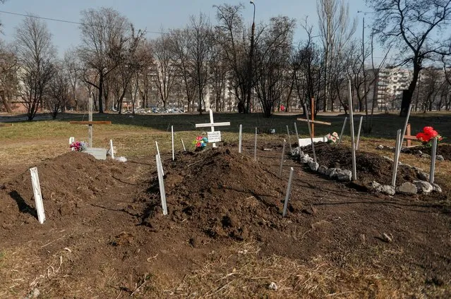 Graves of residents killed by shelling during Ukraine-Russia conflict are seen in a yard, in the besieged southern port of Mariupol, Ukraine March 23, 2022. (Photo by Alexander Ermochenko/Reuters)