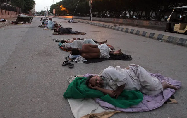 Pakistani rickshaw drivers and vendors sleep in the open on deserted streets during hot summer weather in Karachi, Pakistan, early Friday, May 20, 2016. Various parts of the country continued to experience an intense heat wave, with the temperatures reaching 48 degree Celsius (118 Fahrenheit) in Larkana and other cities. (Photo by Fareed Khan/AP Photo)