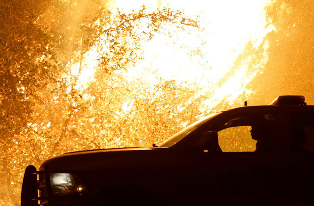 A firefighter drives away from the flames as Park Fire burns near Chico, California on July 25, 2024. (Photo by Fred Greaves/Reuters)