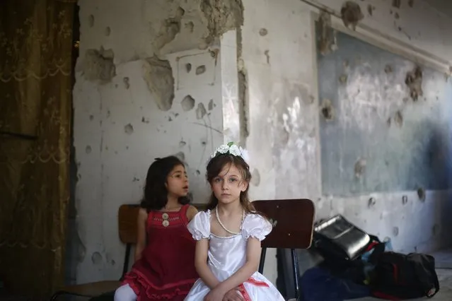 A picture made available on 22 May 2016 shows girls attending the seminar, Douma, Outskirts of Damascus, Syria, 21 May 2016. The Office of Education in Douma City created an art Gallery for a damaged school prior to its bombing and what remains from it after more than 15 child and the manager of the school Ms. Iman Abd al-Nagee got killed in an airstrike on 13 September 2015. A seminar was held entitled “The Childhood in the United Nations, Betweens dreams and reality”, the seminar was hosted by young girls discusing and telling stories and the bad situation they lived through their childhood. (Photo by Mohammed Badra/EPA)