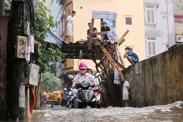 People ride on a motorcycle in a flooded alley in Hanoi, Vietnam, 25 May 2016. (Photo by Luong Thai Linh/EPA)