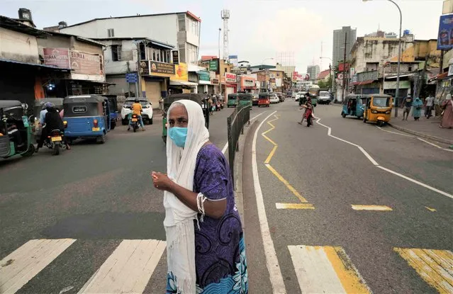 A Sri Lankan woman crosses a street, before the beginning of curfew in Colombo, Sri Lanka, Saturday, April 2, 2022. (Photo by Eranga Jayawardena/AP Photo)