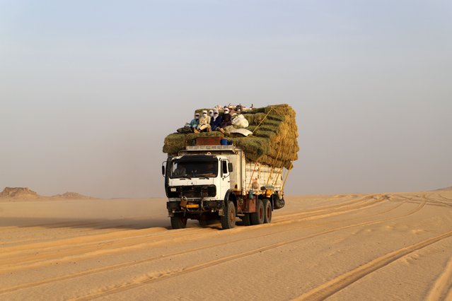 A truck carrying food for humanms and animals crossing the Sahara desert are seen in the area of Djado in Niger, towards the Libyan border, on May 22, 2023. At the edge of an oasis swallowed by the dunes where rare caravans still pass, the desert is dotted with holes. The salt pans of Kalala, located near Bilma in northeastern Niger, were once an essential stop on caravan routes. Long before uranium and the gold rushes, salt was for a long time the main wealth extracted from the subsoil of the Niger Sahara. A once thriving business, which seeks to survive in a disrupted regional economy. (Photo by Souleymane Ag Anara/AFP Photo)