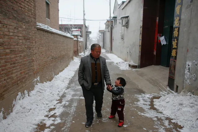 Villager Ding walks with his daughter near their house in the village of Nansitou, Hebei province, February 22, 2017. (Photo by Thomas Peter/Reuters)