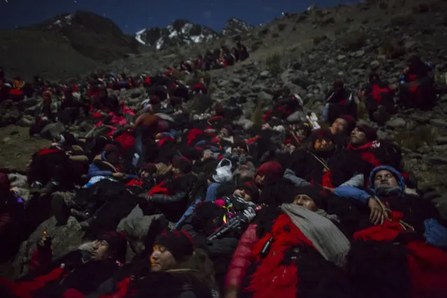In this May 24, 2016 photo, men dressed as “Ukukus”, mythical half-man, half-bear creatures, huddle together to keep warm, as they take a break from their spiritual trek to the top of the Qullqip'unqu mountain, as part of the syncretic three-day festival Qoyllur Rit’i, translated from the Quechua language as Snow Star, in the Sinakara Valley, in Peru's Cusco region. On the last night of the festival, the ukukus climb more than 4,500 meters in freezing temperatures to the mountain’s glacier, carry crosses up the slope to spend the night at the top. They later descend with their crosses as the first rays of the morning sun spread across the mountain range and are met by reception groups of women and children. (Photo by Rodrigo Abd/AP Photo)