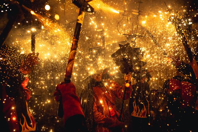 Fire runners in devil costumes gather to enlighten their stick mounted firecrackers during a “Correfocs” in Barcelona's Gracia neighborhood, Spain on May 27, 2023. (Photo by Matthias Oesterle/Rex Features/Shutterstock)