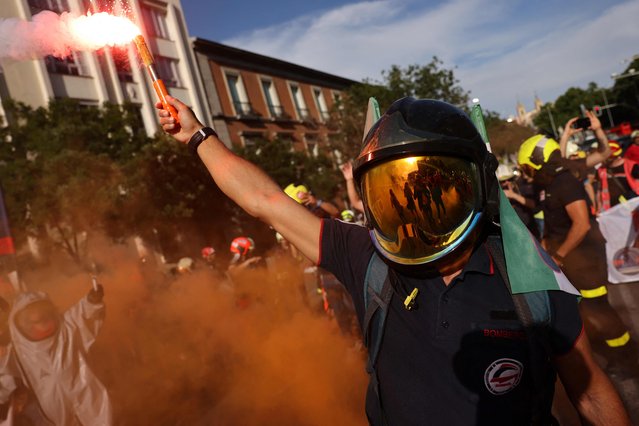 Firefighters hold flares as they protest against a political blocking of a law that would allow all fire-fighting services to be coordinated, in front of the Spanish Congress in Madrid on May 16, 2023. (Photo by Pierre-Philippe Marcou/AFP Photo)