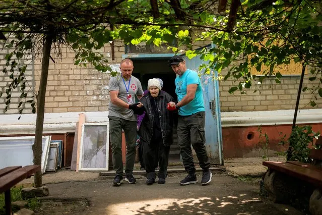 A woman is evacuated by volunteers of Vostok SOS charitable organisation in Kramatorsk, eastern Ukraine, Thursday, May 26, 2022. Residents in villages and towns near the front line continue to flee as fighting rages in eastern Ukraine. (Photo by Francisco Seco/AP Photo)